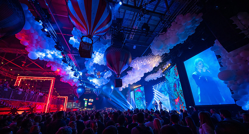 fans watching people onstage with hot air balloons up in the ceiling